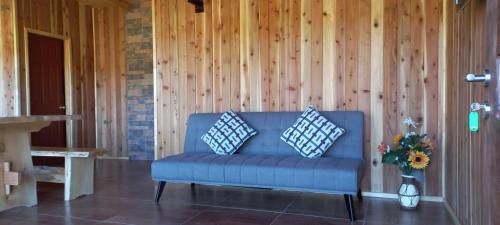 a blue couch with two pillows in a living room at Paraíso Liumalla Lodge in Villarrica