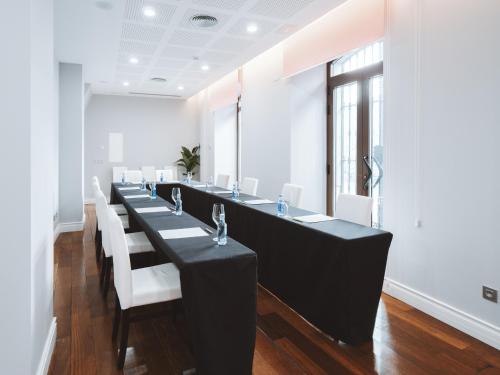 a dining room with a long table and white chairs at Hotel El Coloquio in Valladolid