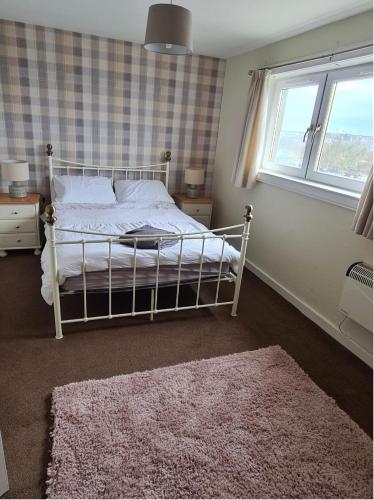 1 dormitorio con cama, ventana y alfombra en North Coast Property - Number 15, en Thurso