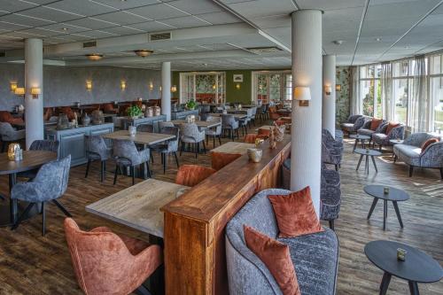 a restaurant with tables and chairs and a bar at Landgoed Hotel Tatenhove Texel in De Koog
