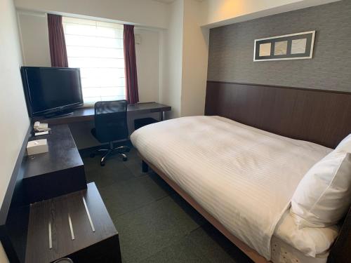 a hotel room with a bed and a desk with a computer at Smile Hotel Nagoya Sakae in Nagoya