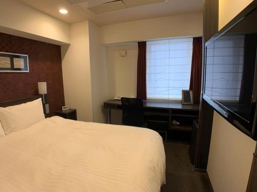 a hotel room with a bed and a desk at Smile Hotel Nagoya Sakae in Nagoya
