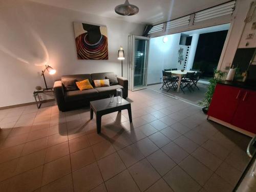 un soggiorno con un divano e un tavolo di Antilo - appartement proche mer a Le Diamant