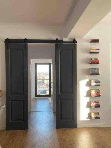 a room with two doors and a wall with books at Modern 2-bedroom apartment in new residence in Craiova