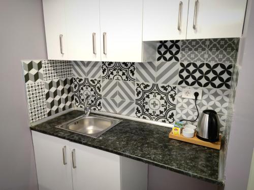 a kitchen with a sink and black and white tiles at Olen Altunizade Hotel in Istanbul