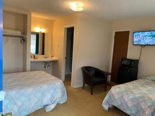 um quarto de hotel com duas camas e uma cadeira e uma televisão em Alpine Lakeview Motel Room WiFi,Sandy beach Boat Ramp,Pier,Marina,Bath House with Laundromat em Hemphill