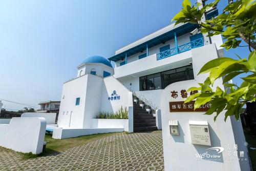 um edifício branco com um farol em frente em Blue White em Wujie