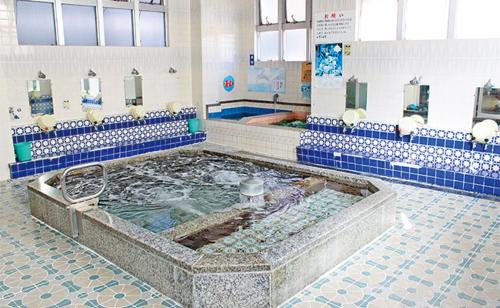 a large tub of water in a bathroom with blue tiles at 四国旅行のHUB拠点 古民家ゲストハウス heso camp in Miyoshi