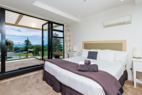 a bedroom with a large bed and a large window at Silver Sands - Beachside Apartment in Nelson