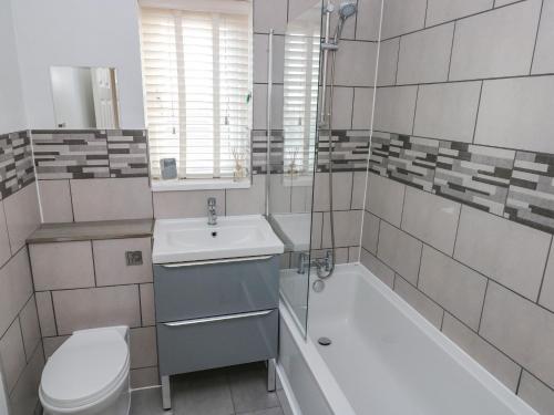a bathroom with a sink and a tub and a toilet at Sandy Bay House in Saundersfoot