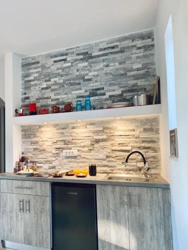 a kitchen with a sink and a stone wall at Marmaraki Village House & Apartments in Kardamaina