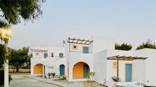 a white house with blue doors and windows at Marmaraki Village House & Apartments in Kardamaina