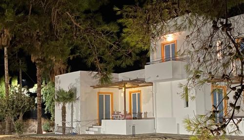 a white house with trees in front of it at Marmaraki Village House & Apartments in Kardamaina