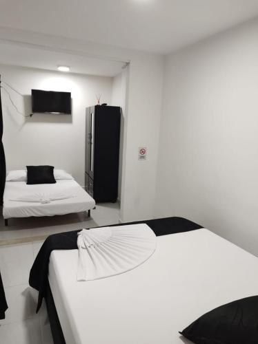 a bedroom with two beds and a black refrigerator at HOTEL BLACK & WHITE in Cali