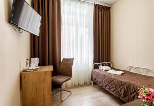 モスクワにあるHotel Andreevskiyのベッド、椅子、テレビが備わるホテルルームです。