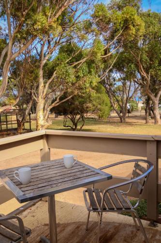 a picnic table with two cups and a chair at BIG4 Cape Jervis Accommodation & Caravan Park in Cape Jervis