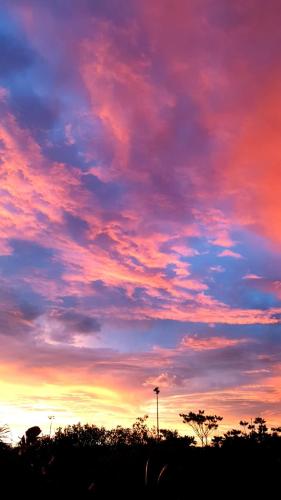 una puesta de sol con un cielo colorido con árboles y un poste en Rising Sun en Russell Island