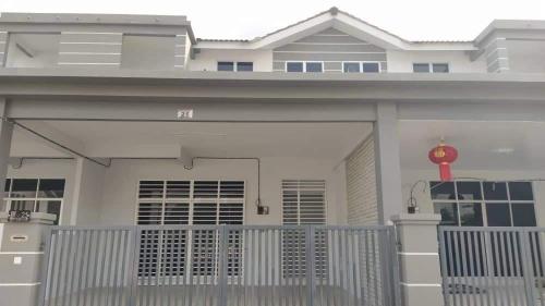 a large white house with a gate and a redozy at Afiyah Guesthouse in Padang Besar
