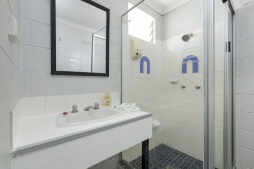 a white bathroom with a sink and a shower at Innisfail City Motel in Innisfail