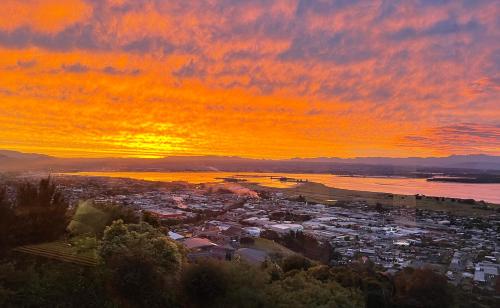 a sunset over a beach with a city and the ocean at Tasman Bay Villa in Nelson