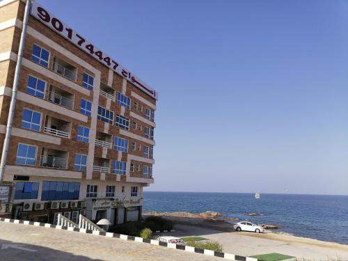 a building by the ocean with a car parked next to it at Amwaj hotel Salalah Mirbat in Salalah