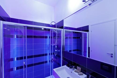 ein blau gefliestes Bad mit einem Waschbecken und einem Spiegel in der Unterkunft Bed & Blues in Torre Lapillo