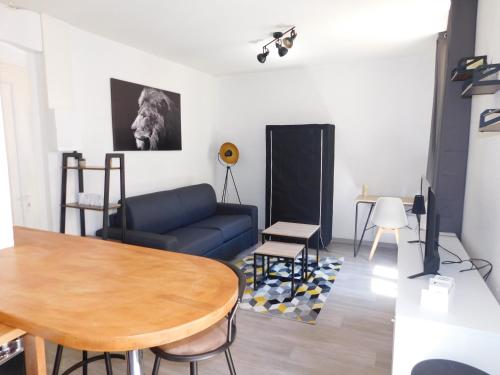 un salon avec un canapé bleu et une table dans l'établissement Appartement tout équipé à 15 min des plages, à Béziers