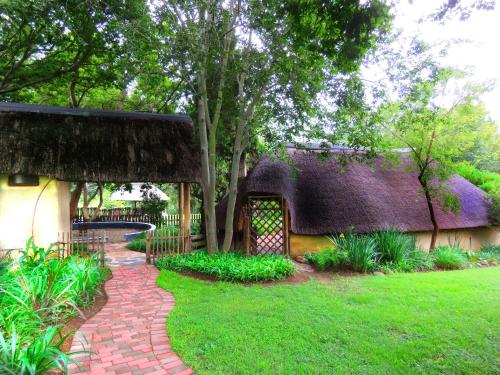 a house with a thatched roof and a brick walkway at Pine Valley in Lanseria