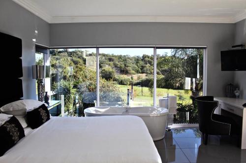 a bedroom with a bed and a tub and a window at North Haven Country Estate in Honeydew