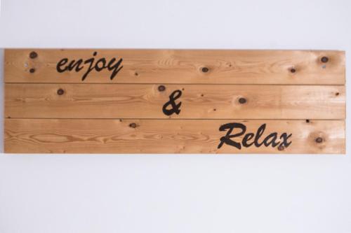 a wooden sign with the word enjoy and relax at Κastro Ηotel in Agios Kirykos