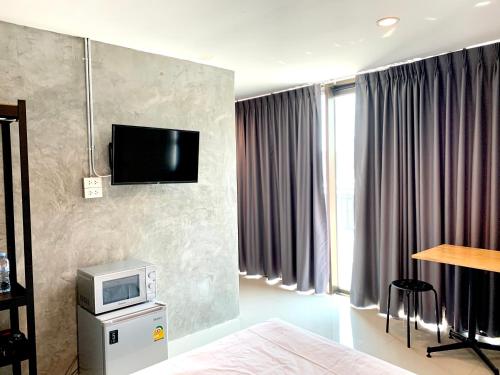 1 dormitorio con 1 cama y TV en la pared en Udomsuk Inn & Cafe Since 2019 - BTS Udomsuk, en Bangkok