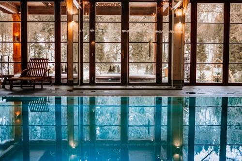 a swimming pool with a chair and windows at Aries Hotel & SPA Wisła in Wisła