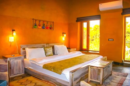 a bedroom with a large bed with orange walls at Prakriti Aalay - Riverside Mountain View Boutique Eco Resort in Dharamshala
