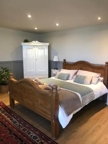 a bedroom with a large wooden bed with pillows at Little Banks Cabin in Ringwood