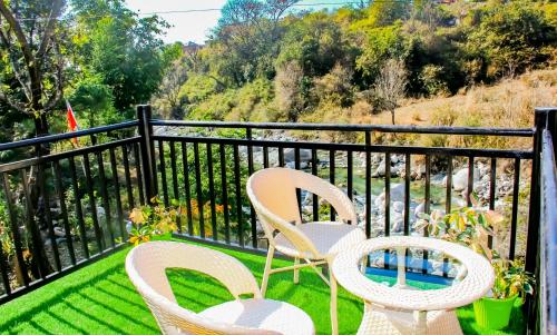 two chairs and a pool on a balcony at Prakriti Aalay - Riverside Mountain View Boutique Eco Resort in Dharamshala
