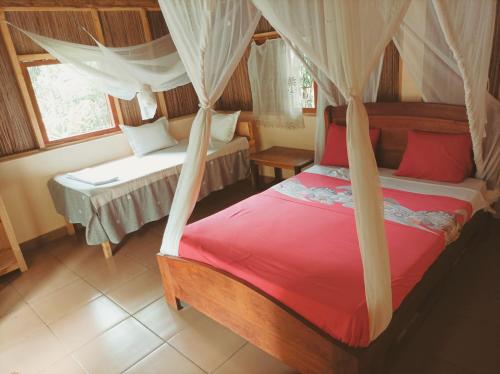 Onja Surf Camp في Mahambo: غرفة نوم بسرير مع مظلة