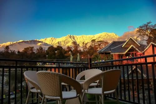 a group of chairs sitting on a balcony with mountains at Prakriti Aalay - Riverside Mountain View Boutique Eco Resort in Dharamshala