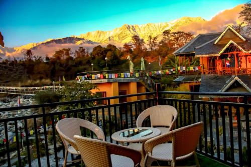 a balcony with chairs and a table and mountains at Prakriti Aalay - Riverside Mountain View Boutique Eco Resort in Dharamshala