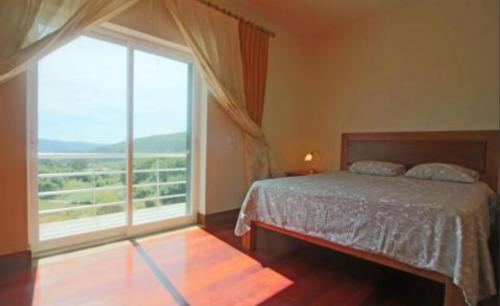 a bedroom with a bed and a large window at Casa Ze da Cotta in Vila Verde