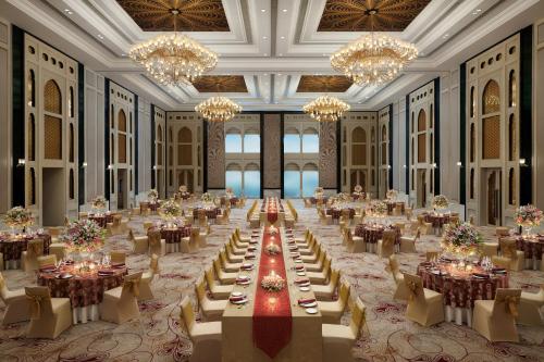 a large banquet hall with tables and chandeliers at The Leela Palace Jaipur in Jaipur