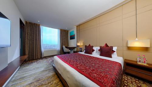 a hotel room with a large bed and a desk at Sayaji Vadodara in Vadodara