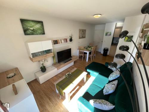 a living room with a couch and a tv at JARDINS DE RAMEL – APPT 2106*** - CURE/SKI WIFI in Luchon