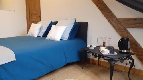 um quarto com uma cama azul e uma mesa em Jules Verne em Amiens
