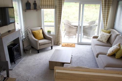 sala de estar con sofá, sillas y chimenea en Honeybee Lodge, en Morpeth