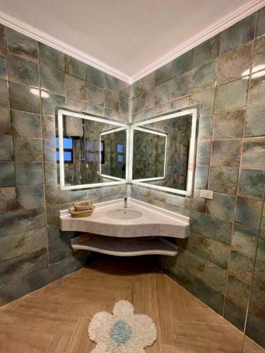 a bathroom with a large sink and two mirrors at Luxurious 3 BR Rustic Apartment Overlooking Huge Garden - For Families and Couples in Cairo