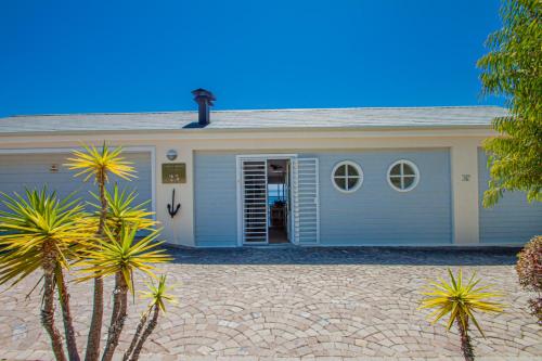 a blue house with a driveway in front of it at A Boat House in Simonʼs Town