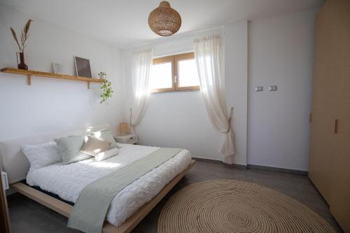 sypialnia z łóżkiem z białą pościelą i oknem w obiekcie Sundinia Home, Vista sul Mare w mieście Porto Torres