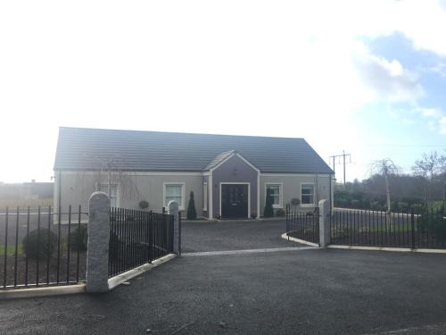 a house with a fence in front of it at Arvalee Retreat With Outdoor HotTub in Omagh