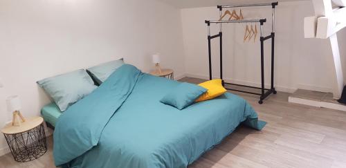- une chambre avec un lit bleu et un oreiller jaune dans l'établissement L'appartement du Jardin Perdoux, à Bergerac
