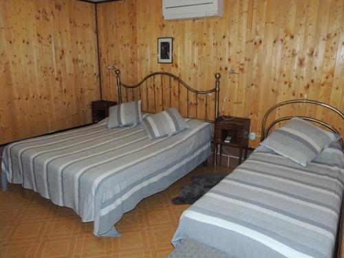 two beds in a room with wood paneled walls at B&B Renè in Pescantina